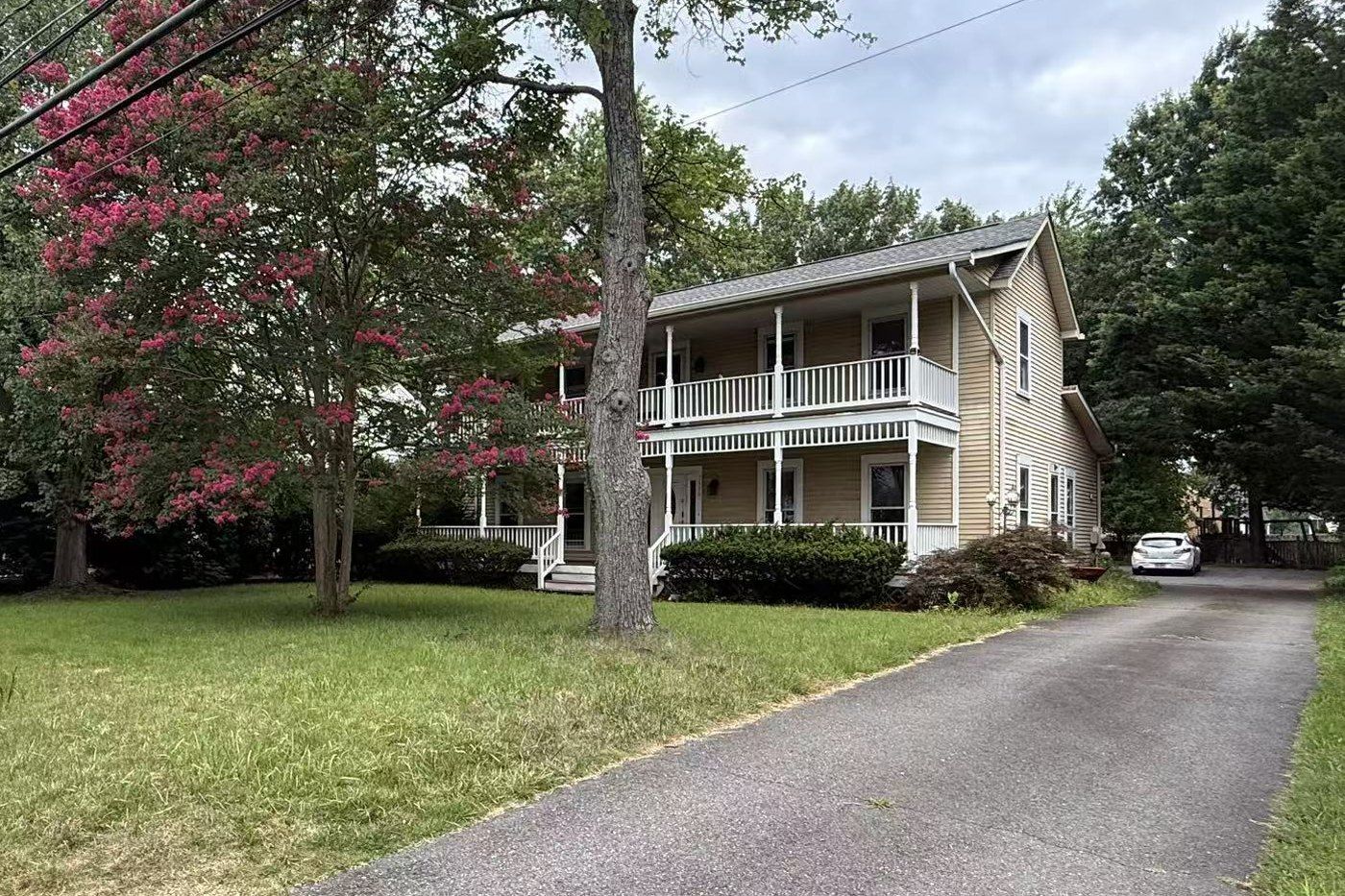 A two-storey house with a wrap-around porch among trees in Dunn Loring, Virginia.